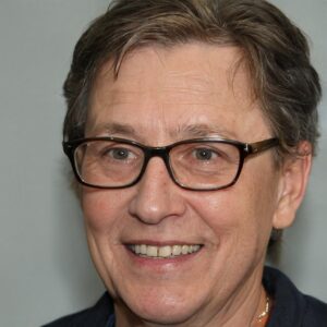 A woman wearing glasses and a blue shirt smiles.