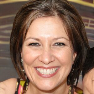A woman smiling while holding a necklace.